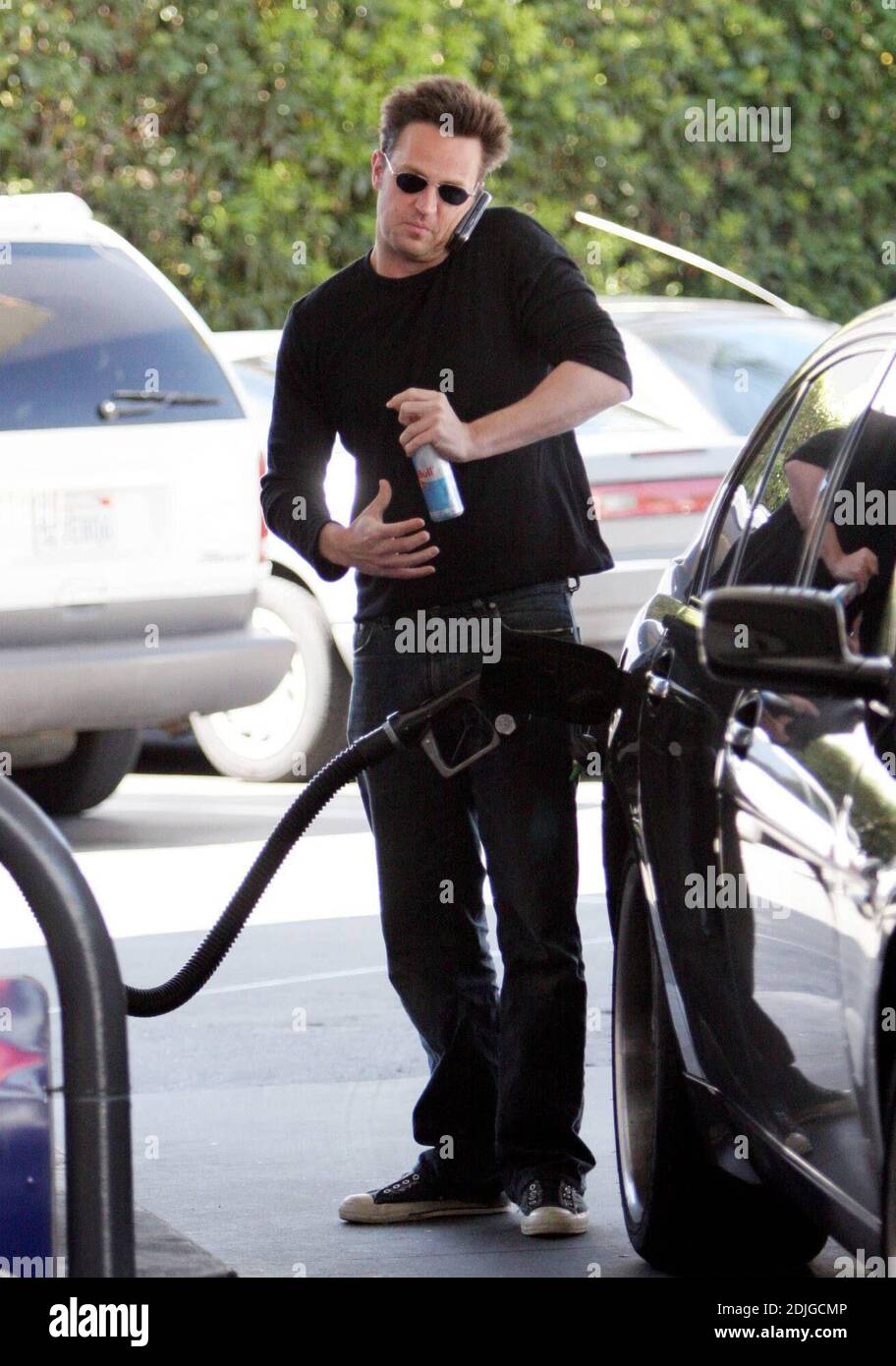 Exclusive!! Matthew Perry mutli tasks in Beverly Hills, Ca. The actor chatted on hi cell phone whilst filling up his gas tank and holding on to a can of the energy drink, diet Red Bull. 03/02/06 Stock Photo