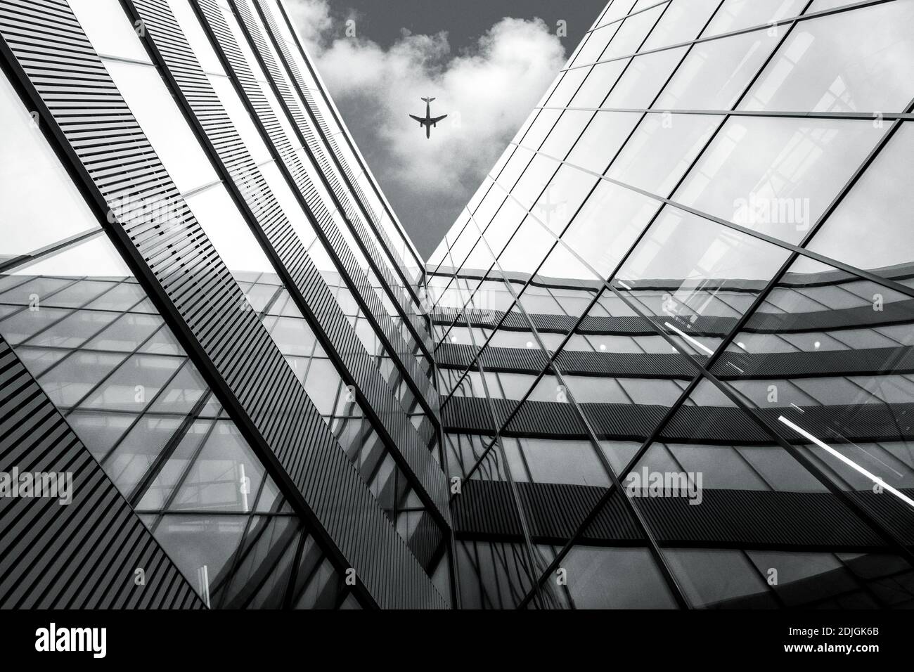 Flying airplane over modern architecture building, low angle black and white high contrast picture Stock Photo