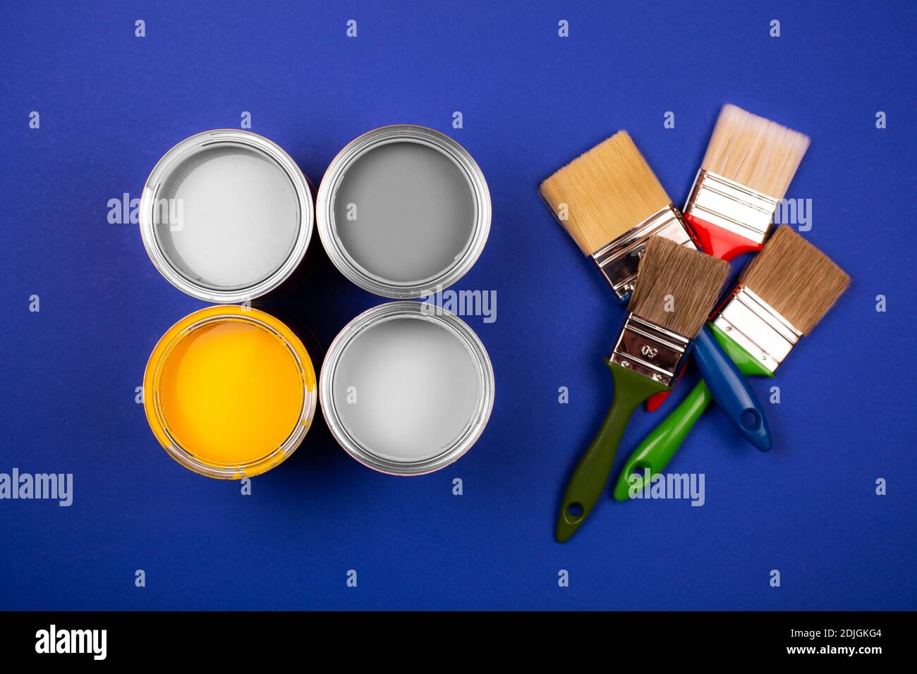 Four open cans of yellow and gray paint with brushes on blue background