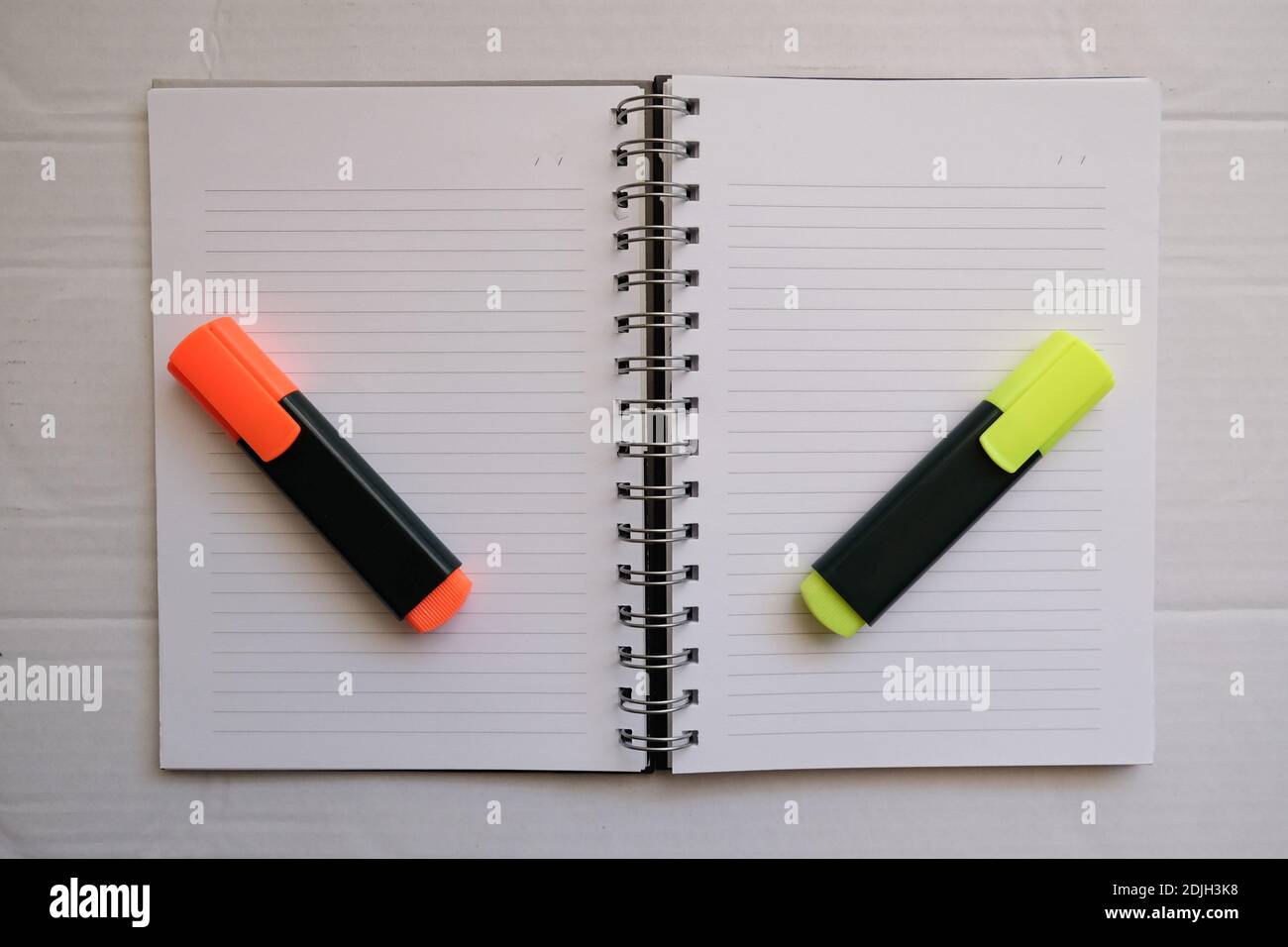 orange and yellow hihglighter on the empty lined notebook. preparation of make a homework.Business work area concept. Stock Photo