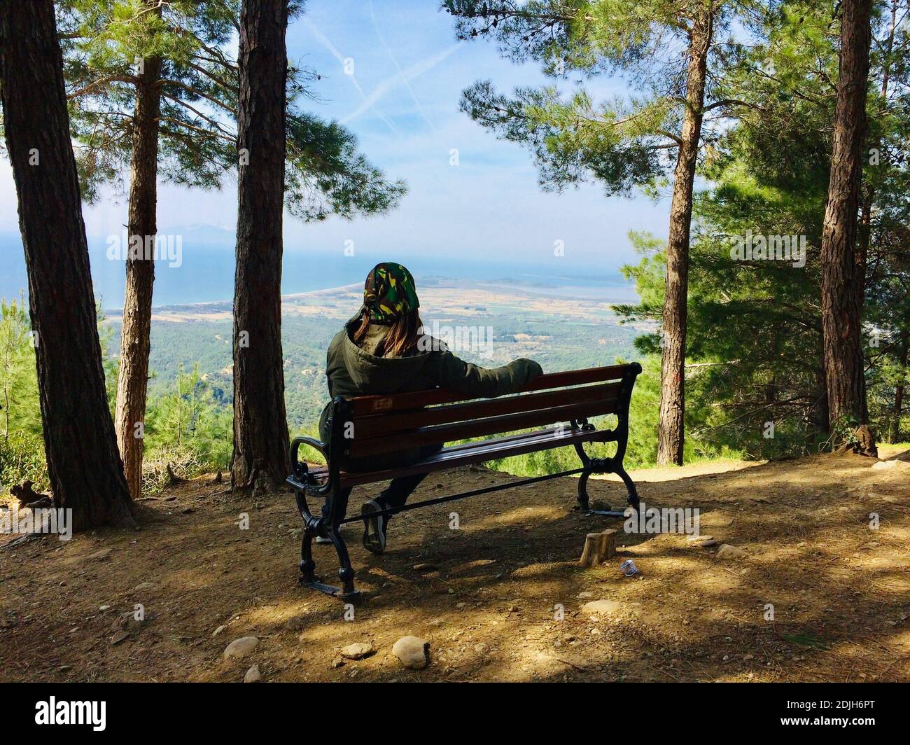 Full Length Of Man Sitting On Bench On Mountain Stock Photo
