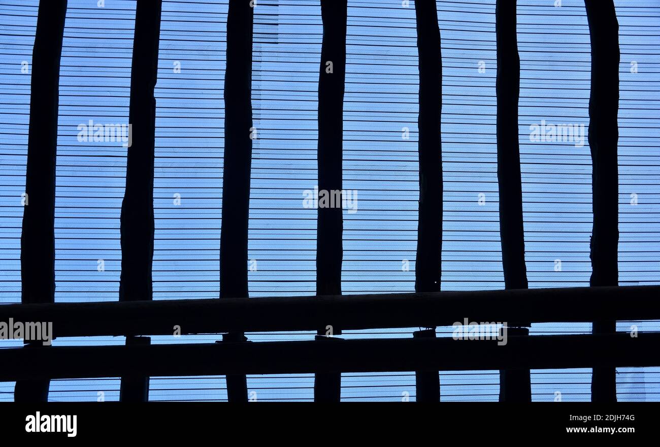Lattice of wooden beams on the roof with metal mesh. Blue sky. Stock Photo