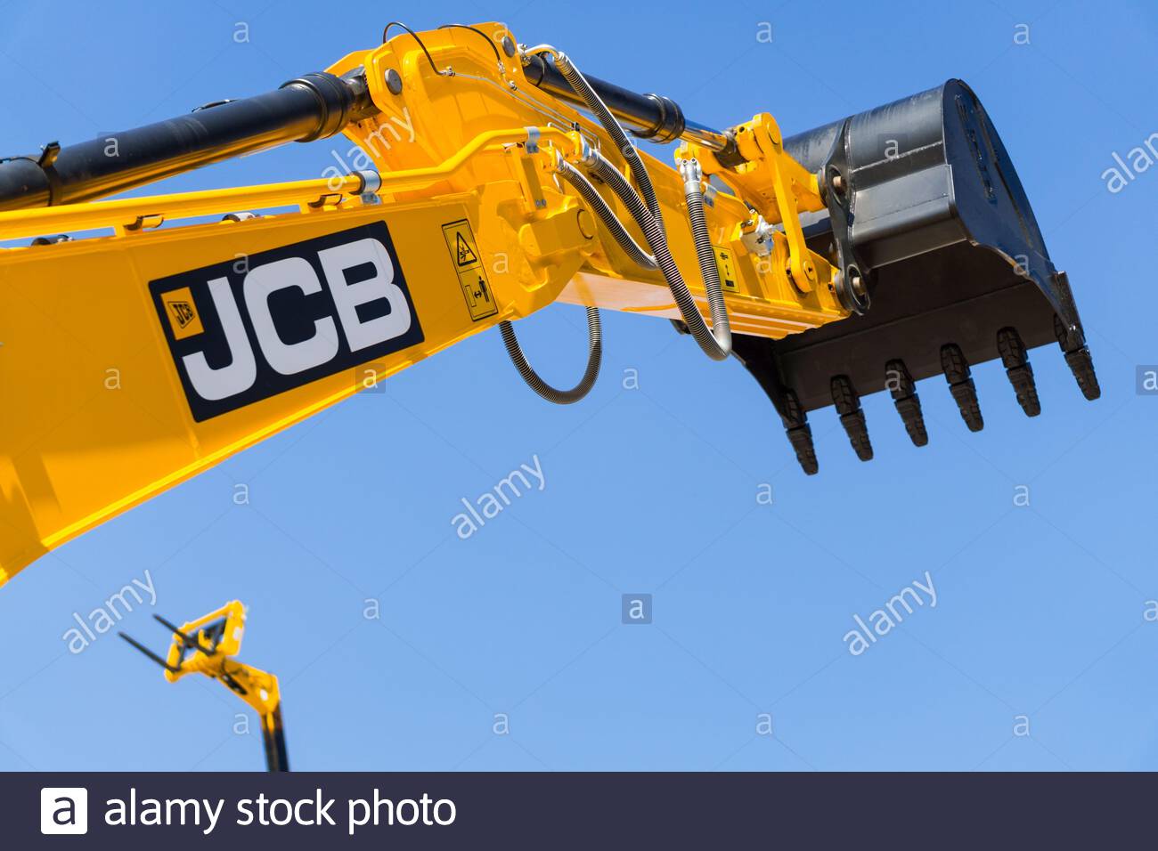 JCB excavator backhoe bucket lifted up on blue sky background Stock Photo Alamy