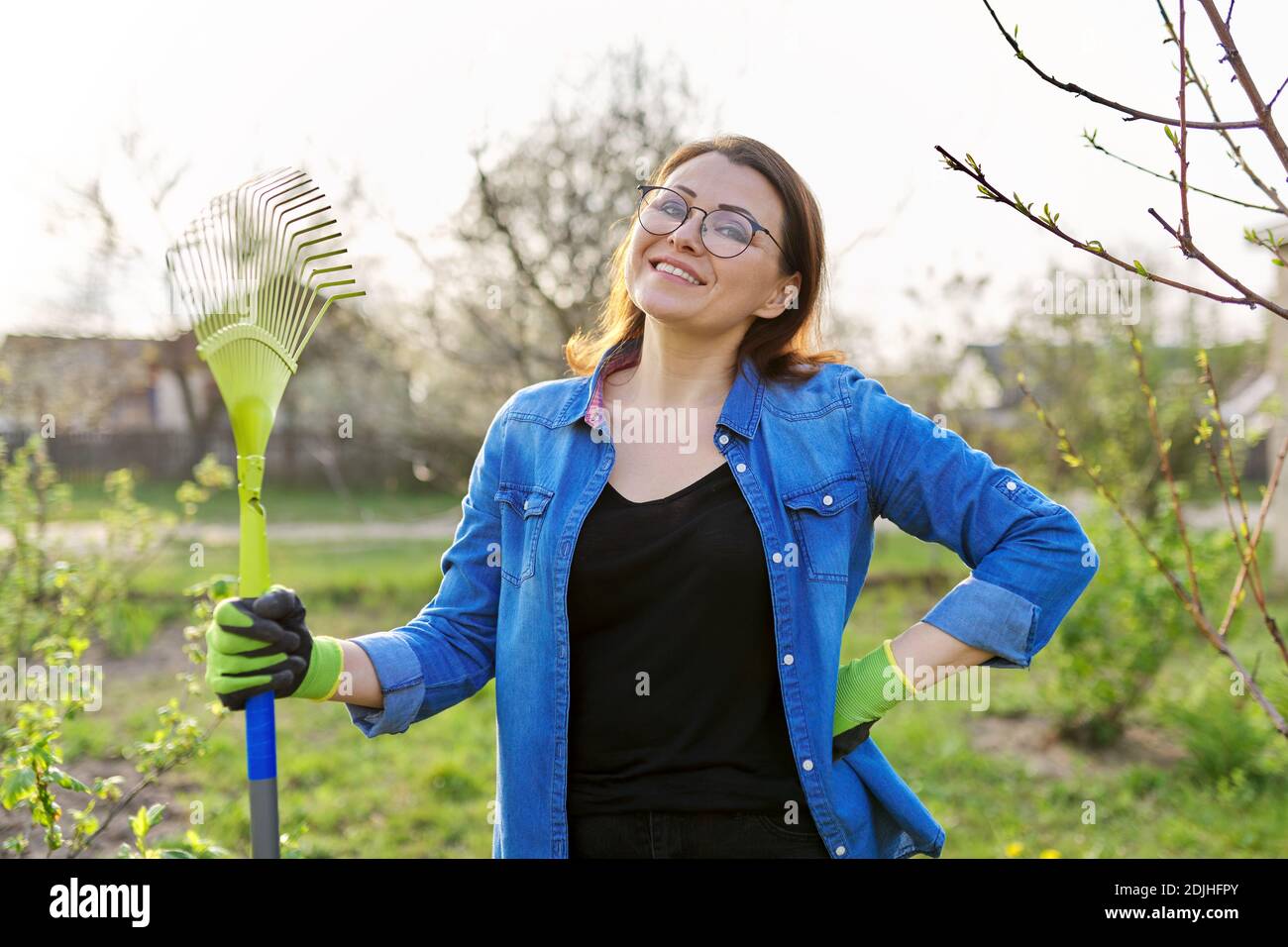 Spring gardening, portrait of mature smiling woman gardener with rake ...