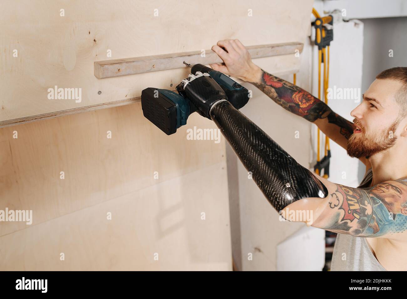 Crafty cyborg man with bionic hand working with cordless electric screwdriver Stock Photo