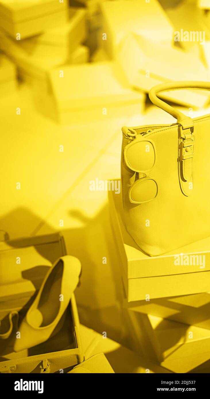 Bright illuminating yellow high heel shoes, handbag and glasses on gray color background. Concept of Color of the Year 2021. Fashion outfit abstract layout. Valentine's day concept. Stock Photo