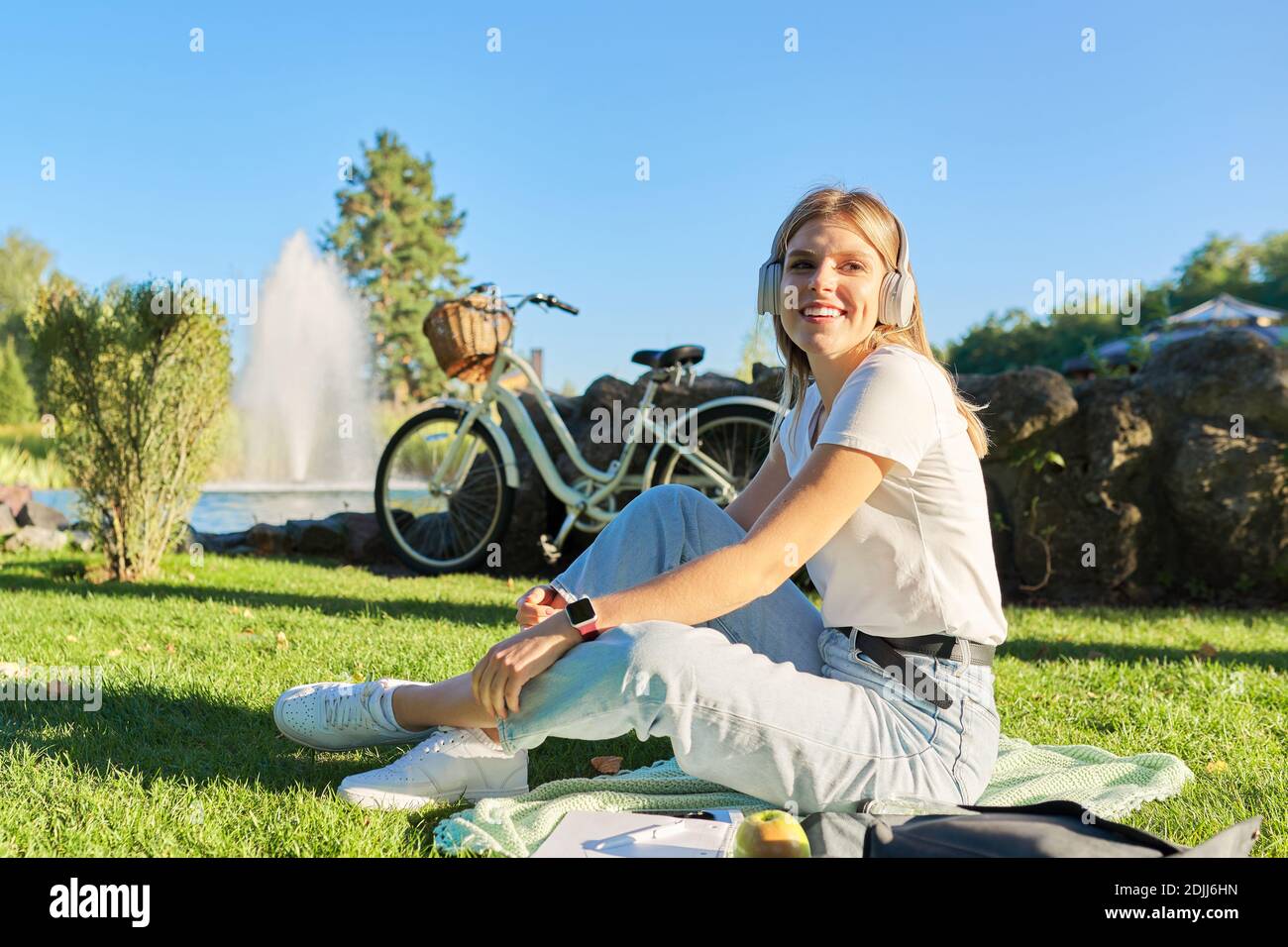 Outdoor portrait of young happy woman in headphones, listening to music ...