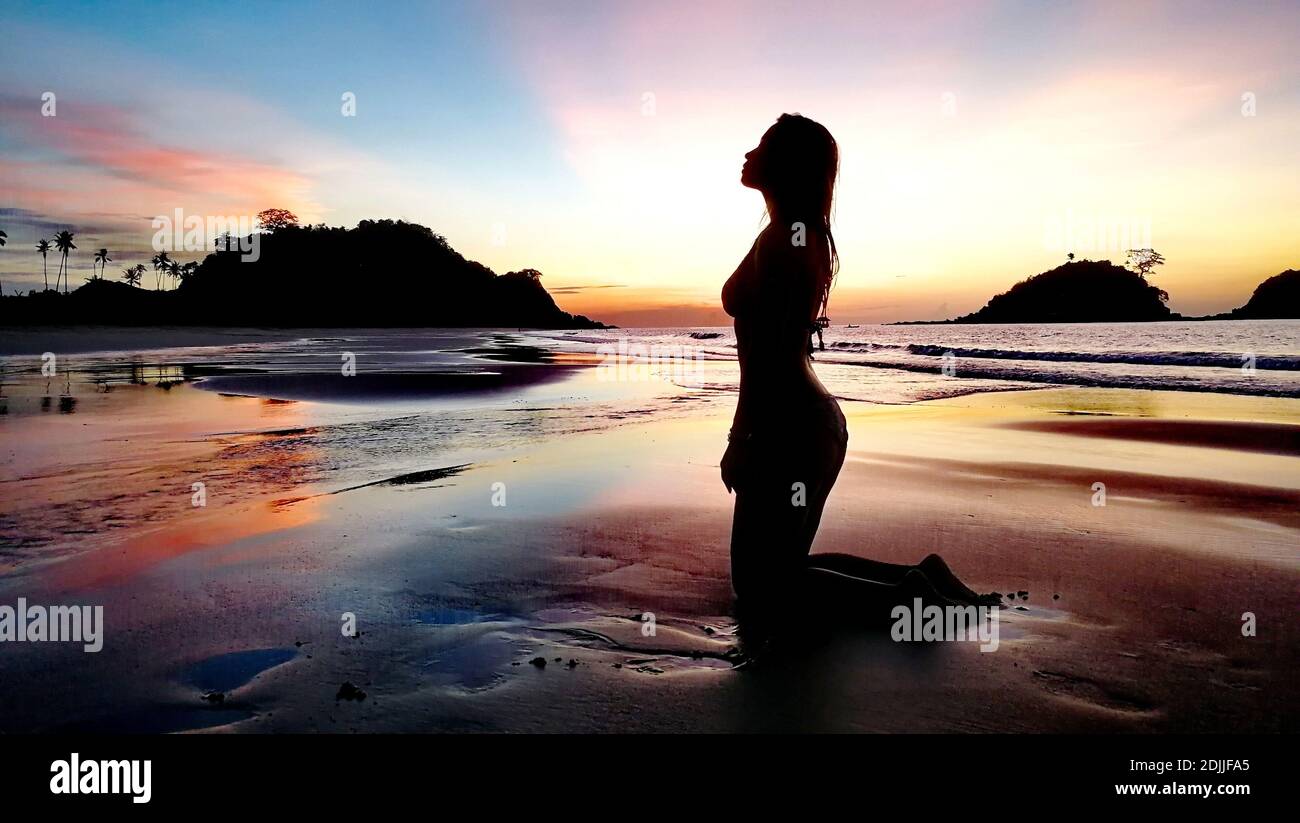 Woman kneeling sand beach sunset beach hi-res stock photography and ...