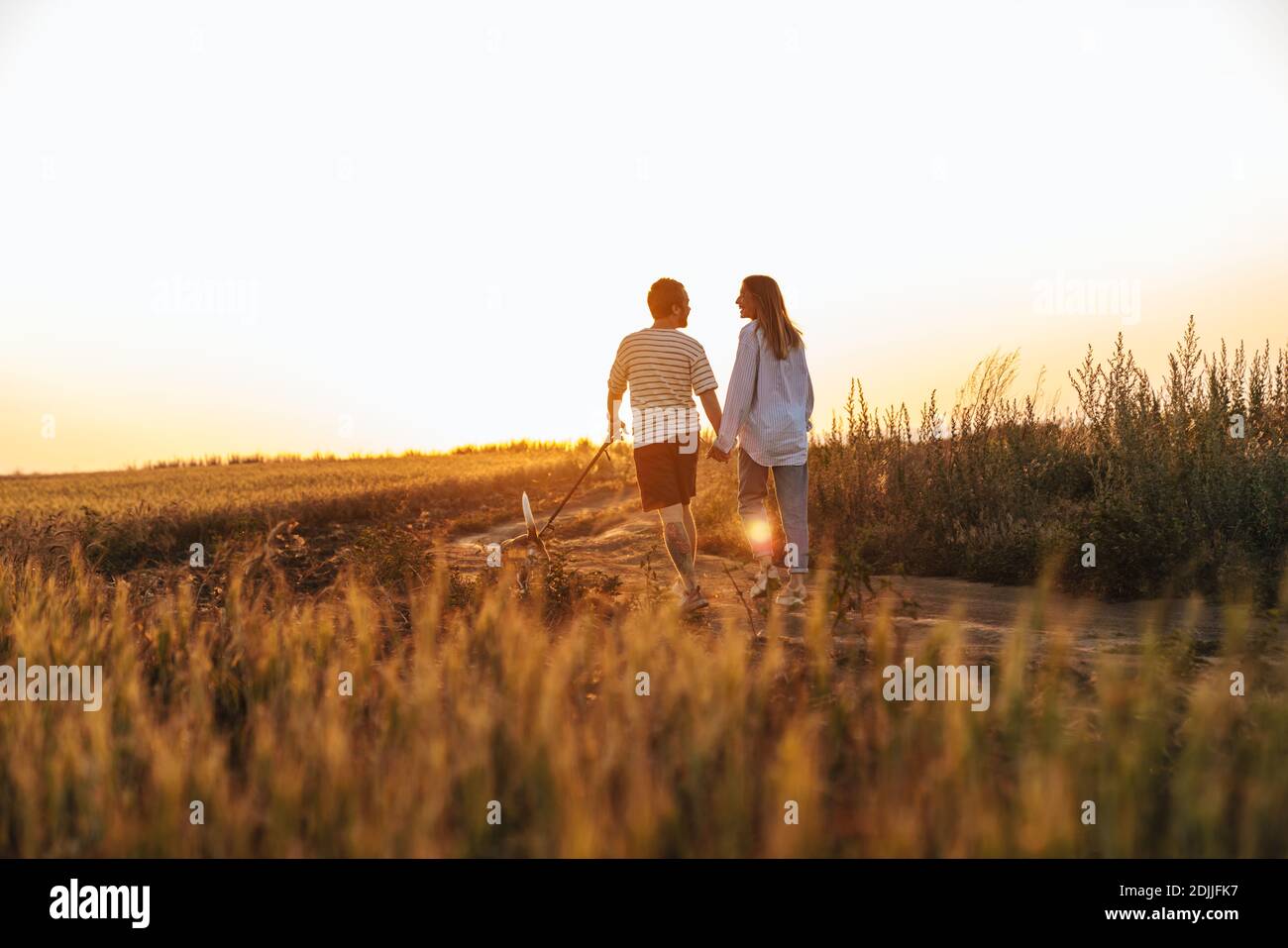 Image of a young loving couple walking with dog outside at the field ...
