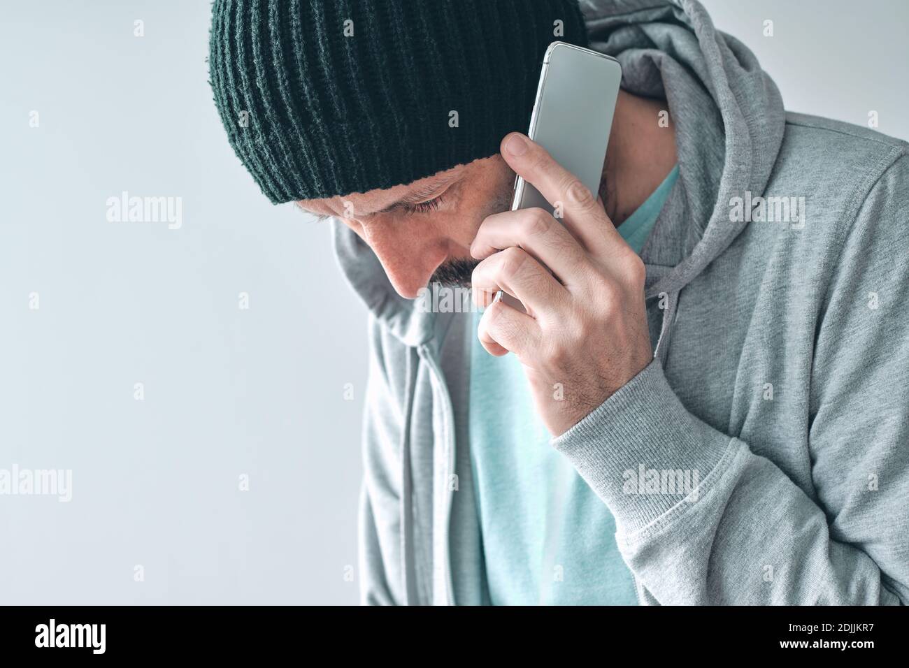 Unhappy man receiving bad news phone call, disappointed casual adult caucasian male talking on mobile phone and looking down, selective focus Stock Photo