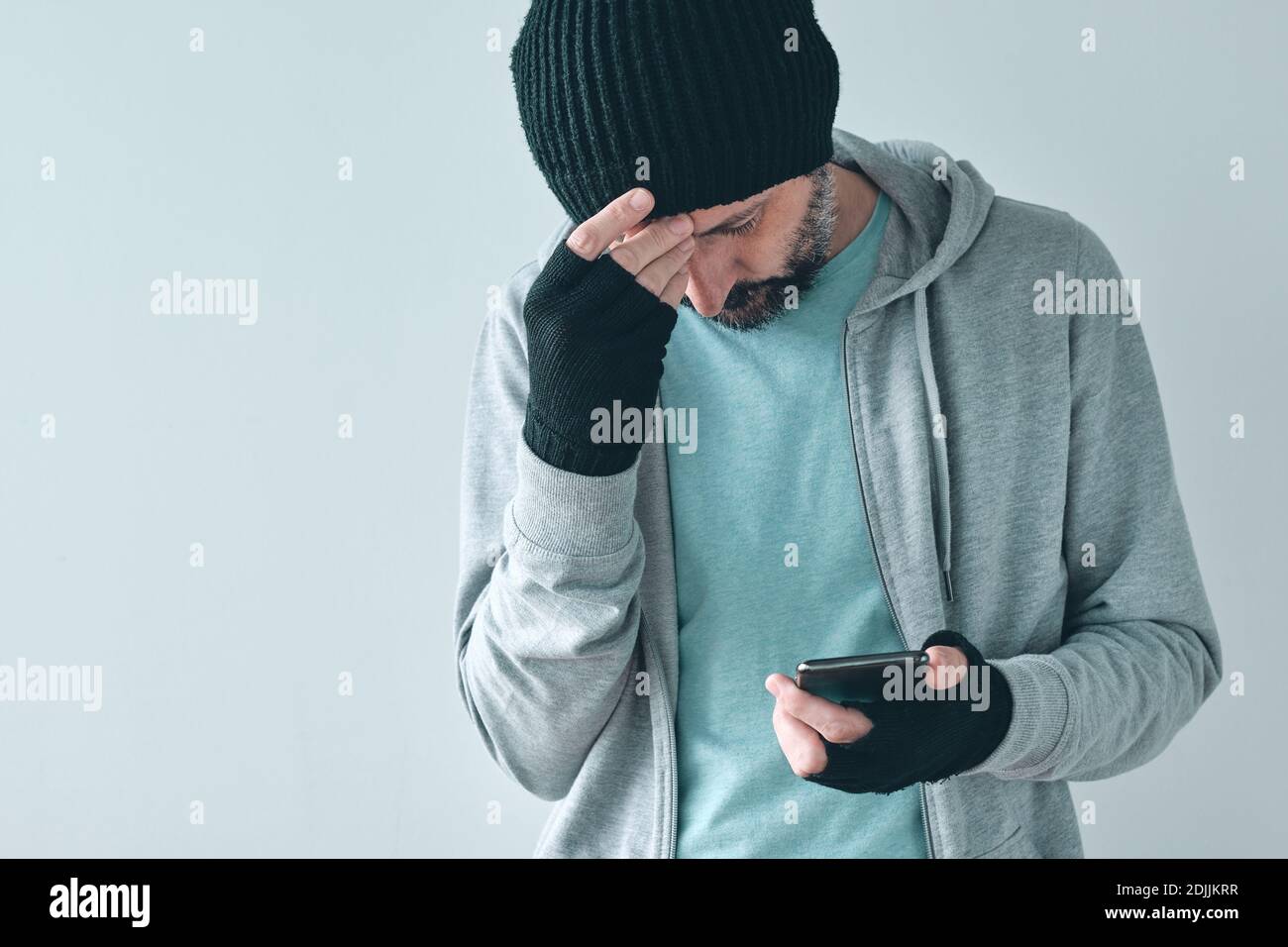 Unhappy man receiving bad news text message, disappointed casual adult caucasian male using mobile phone and looking down, selective focus Stock Photo