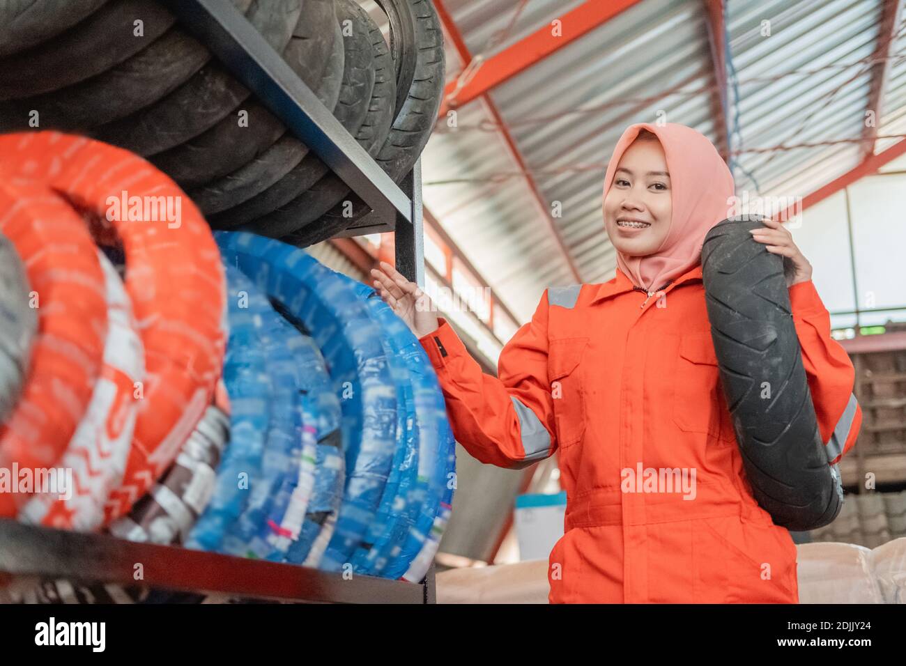 woman wearing a headscarf wearing a wearpack uniform stands beside the tire rack when carrying a
