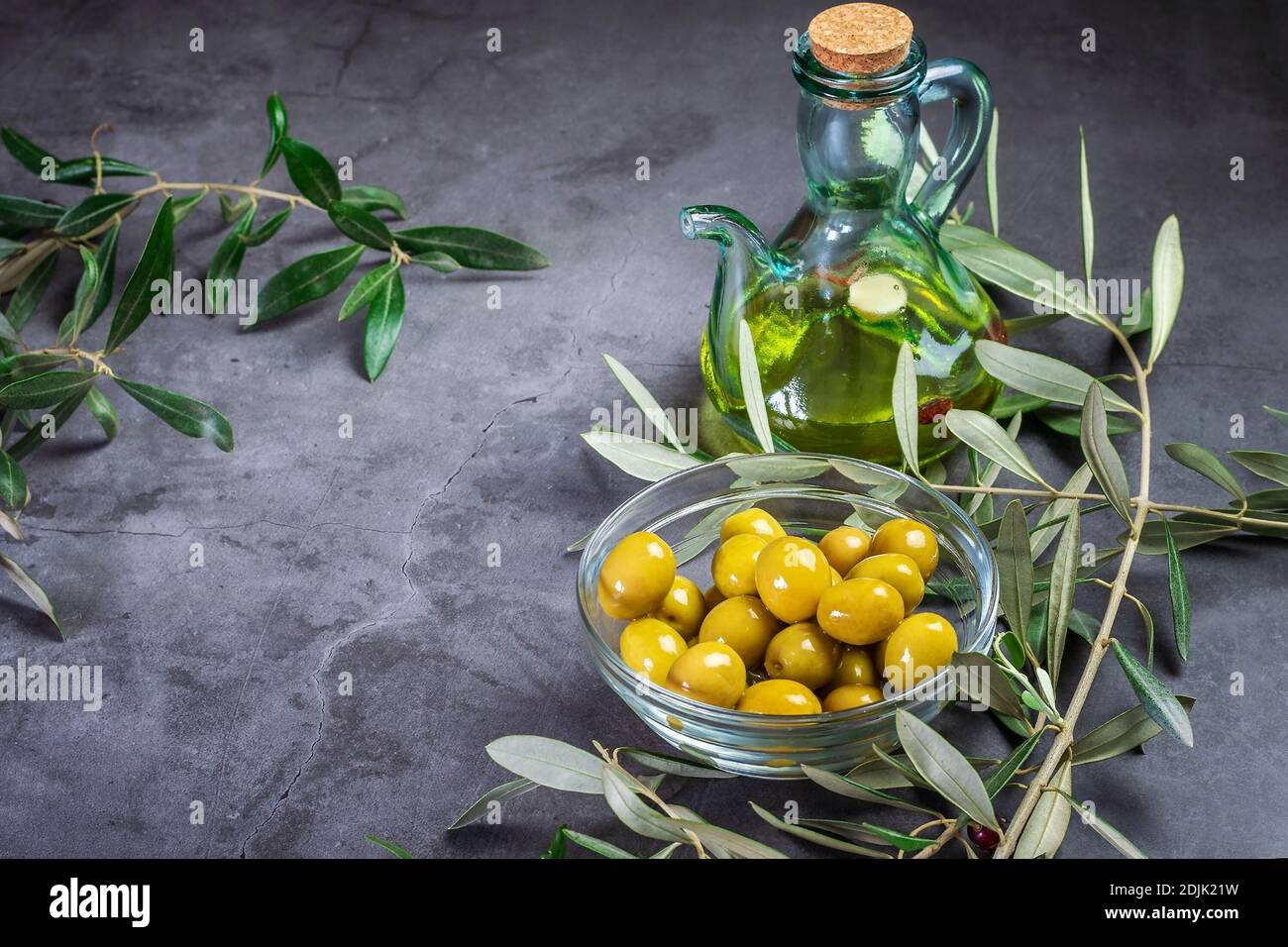 Some fresh ripe olives in a glass bowl and a glass bottle of olive oil ...