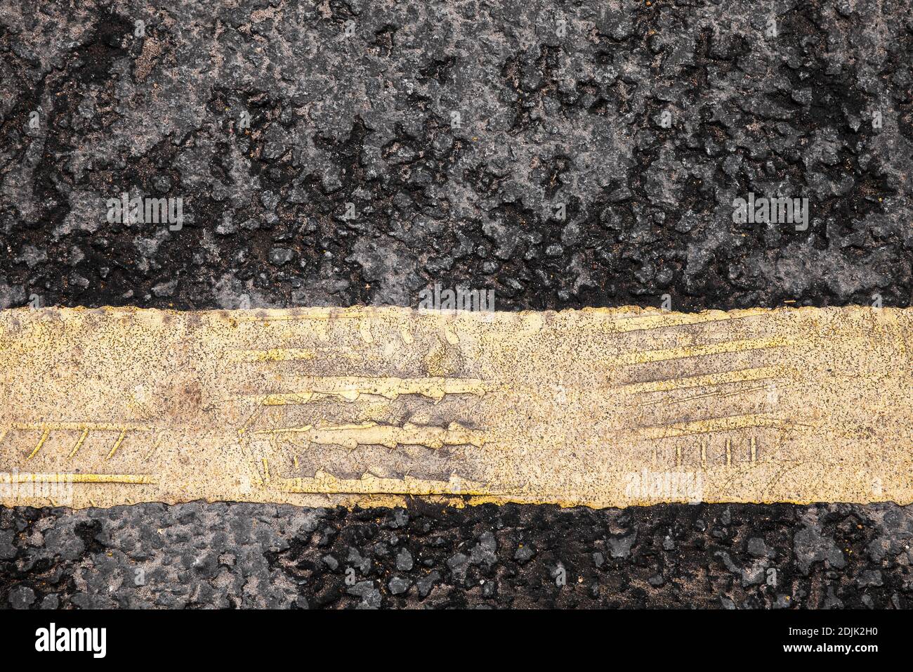 Yellow road marking line with imprinted tire tracks, top view. Transportation background photo texture Stock Photo