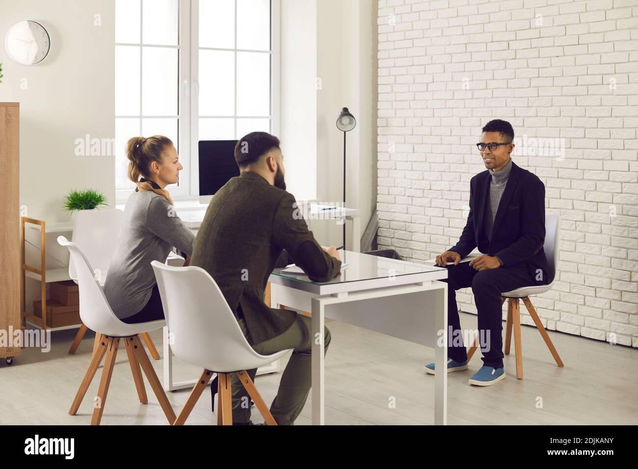 Two HR managers talking to young African-American candidate during job interview Stock Photo