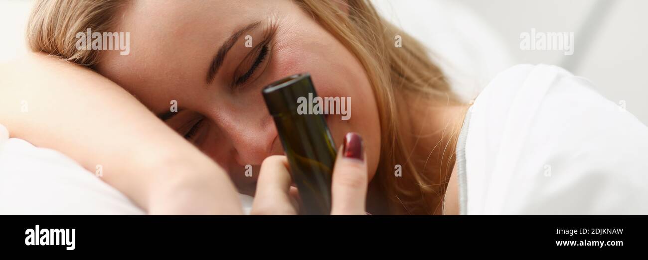 Cheerful young woman with wine waking up after night party Stock Photo
