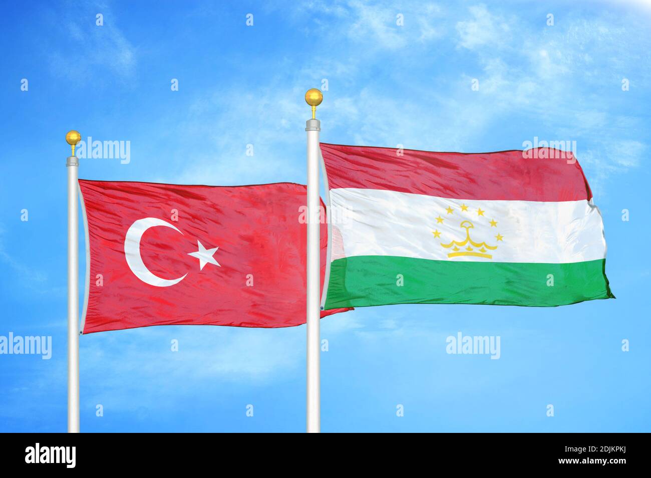 Turkey and Tajikistan two flags on flagpoles and blue cloudy sky Stock Photo