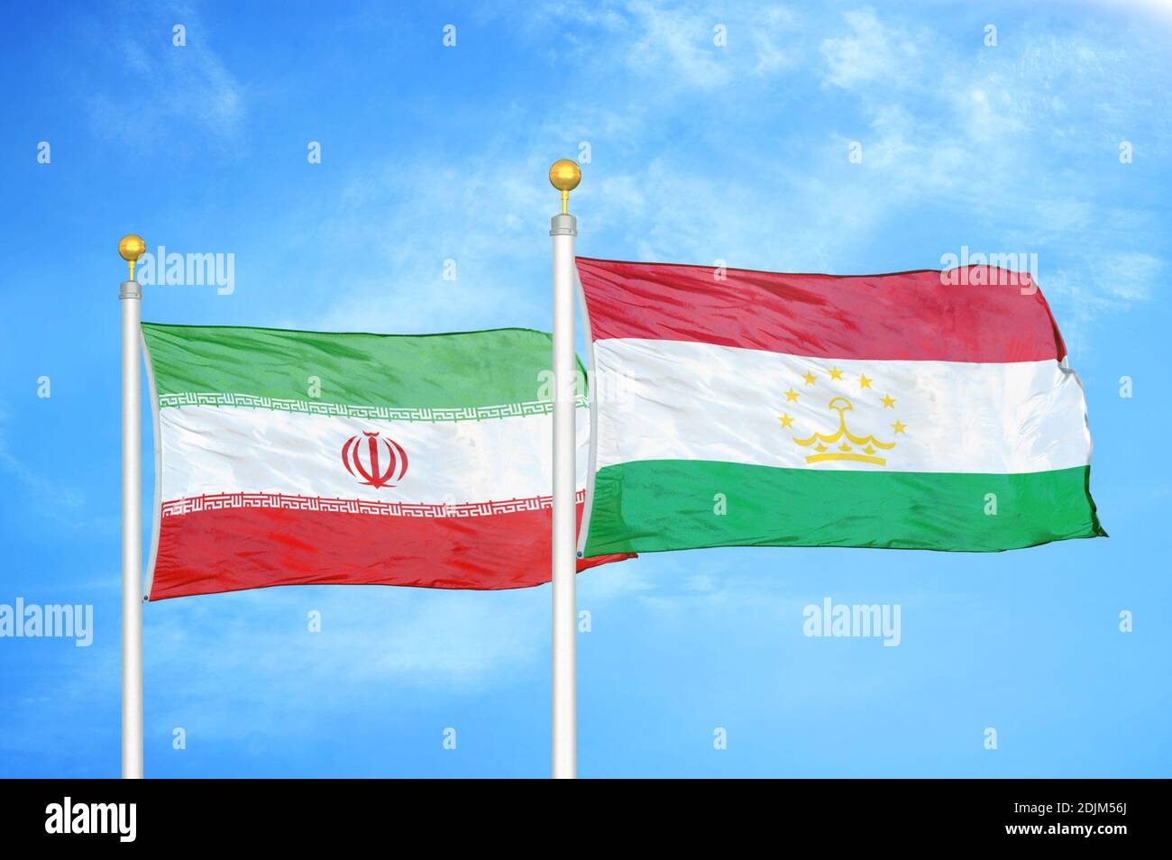 Iran and Tajikistan two flags on flagpoles and blue cloudy sky Stock Photo