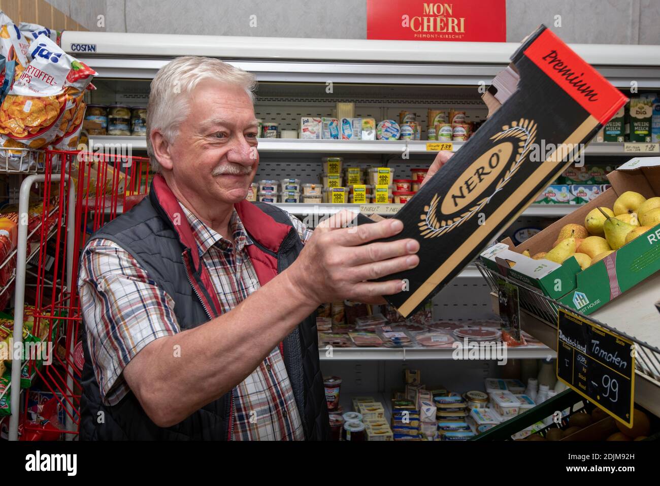 Greengrocer stands a box of tomatoes Stock Photo