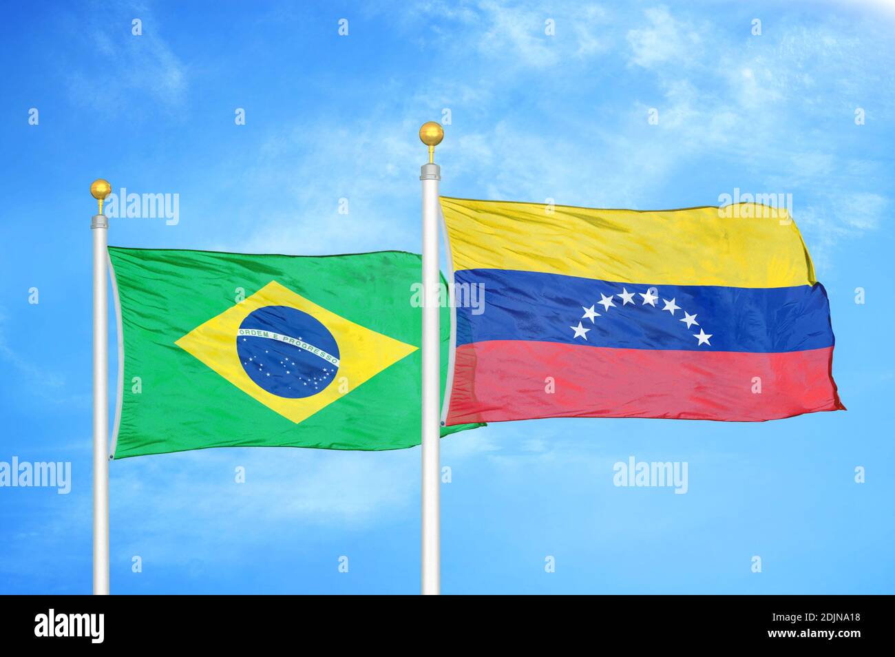 Brazil and Venezuela two flags on flagpoles and blue cloudy sky Stock Photo