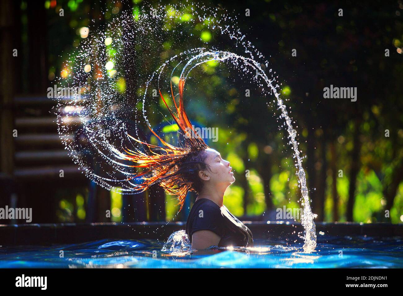 Side View Of Woman Splashing Water From Hair In Swimming Pool Stock