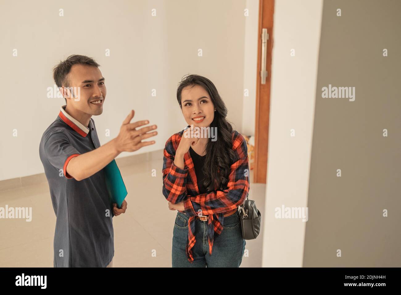 Male housing developers show rooms to female customers while exploring inside a new home Stock Photo