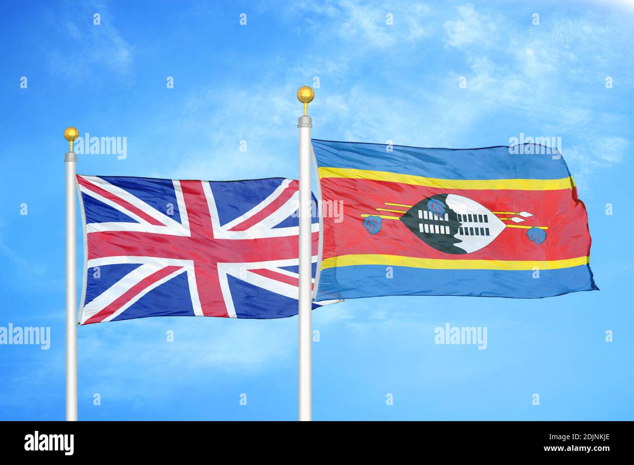 United Kingdom and Eswatini Swaziland two flags on flagpoles and blue cloudy sky Stock Photo
