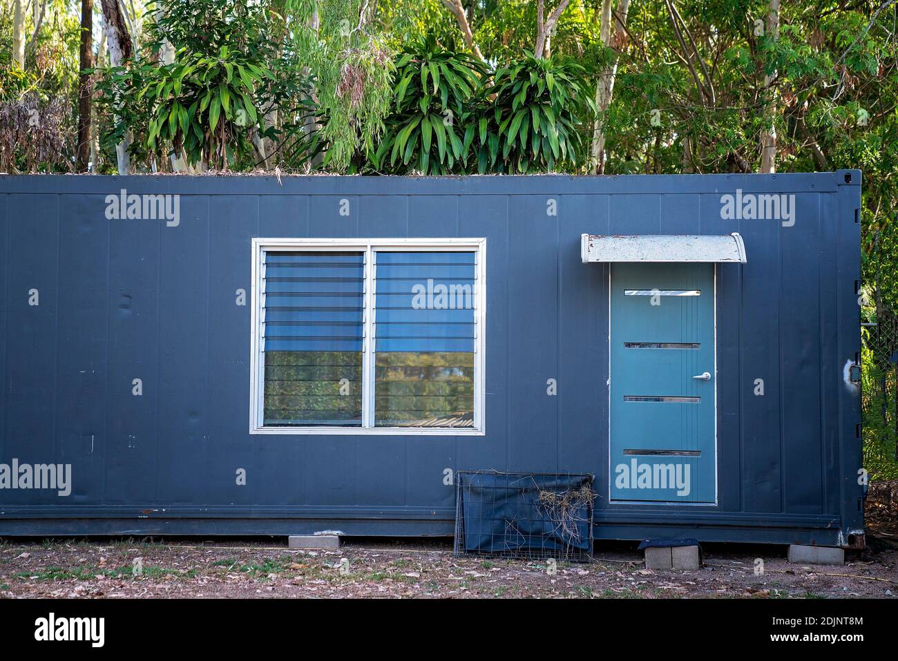 An old metal container converted into a building in a home garden for visiting family and guests Stock Photo