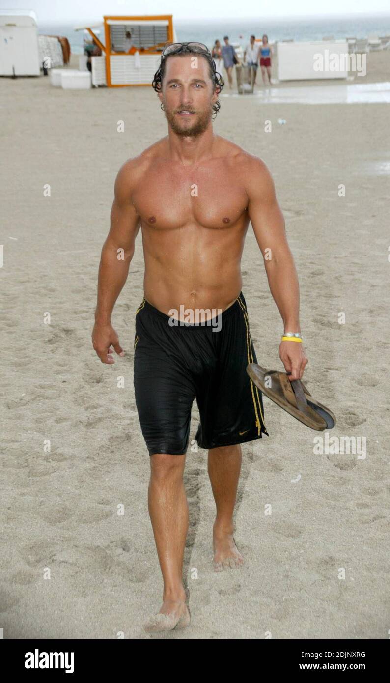 Hunky actor Matthew McConaughey goes for a dip in the ocean during a torrential rain shower, flanked by photographers who hid under an umberella, Miami Beach, FL, 8/24/06 Stock Photo