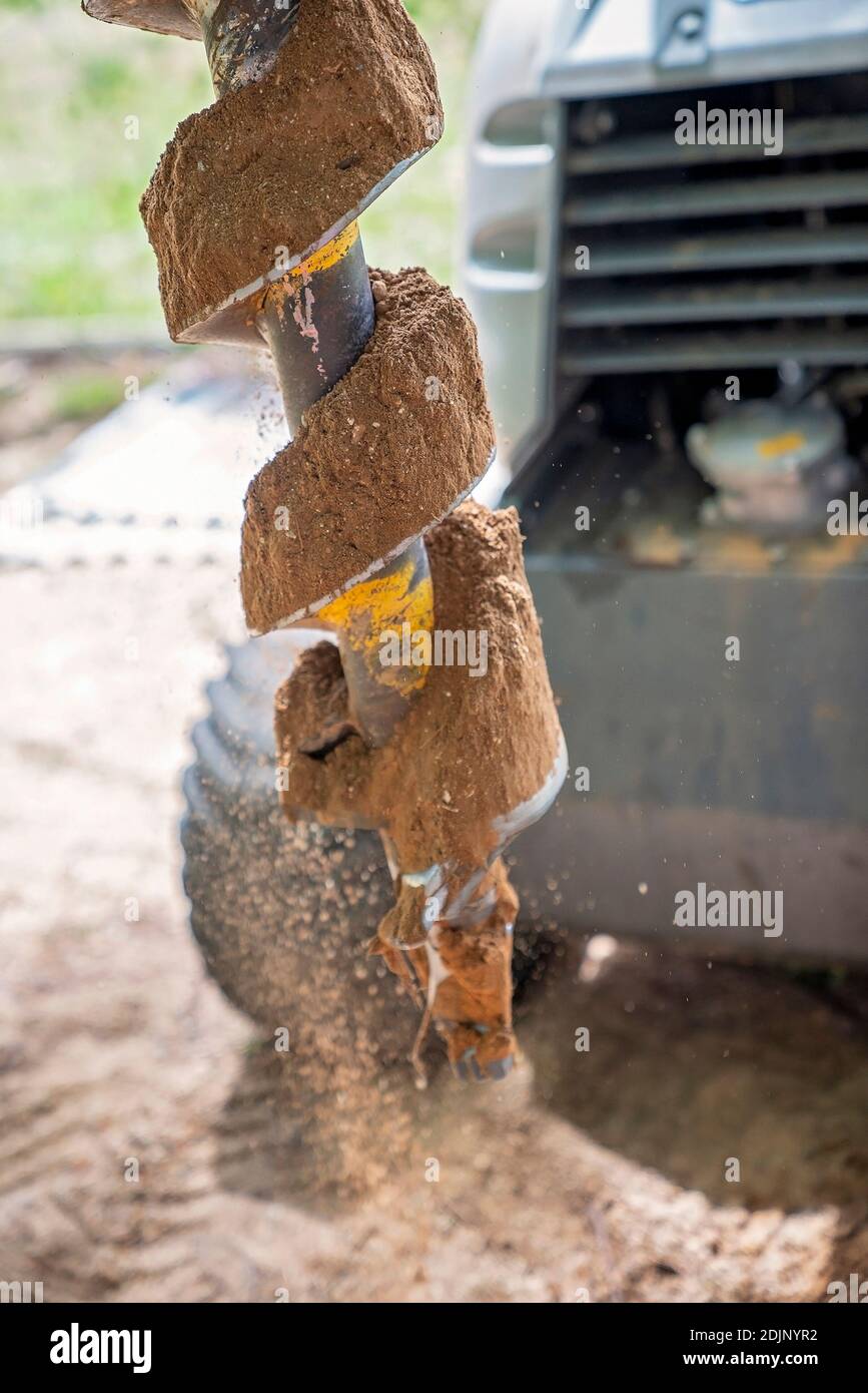 Close up of the rotating blades of a mechanical auger digging post