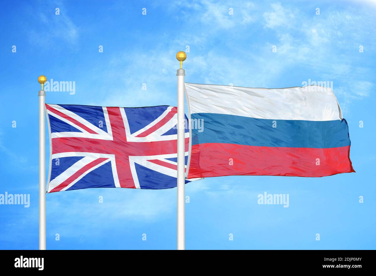 United Kingdom and Russia two flags on flagpoles and blue cloudy sky Stock Photo