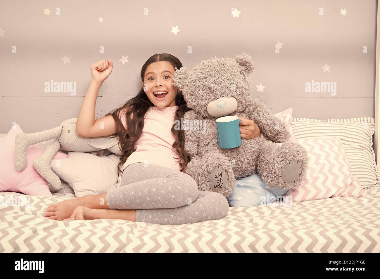 Little child hold mug. Girl in pajamas drinking tea. Relaxation before sleep. Drinking milk just before bed. Bedtime beverage. Hot milk before sleep. Health Benefits Drinking water before bed. Stock Photo