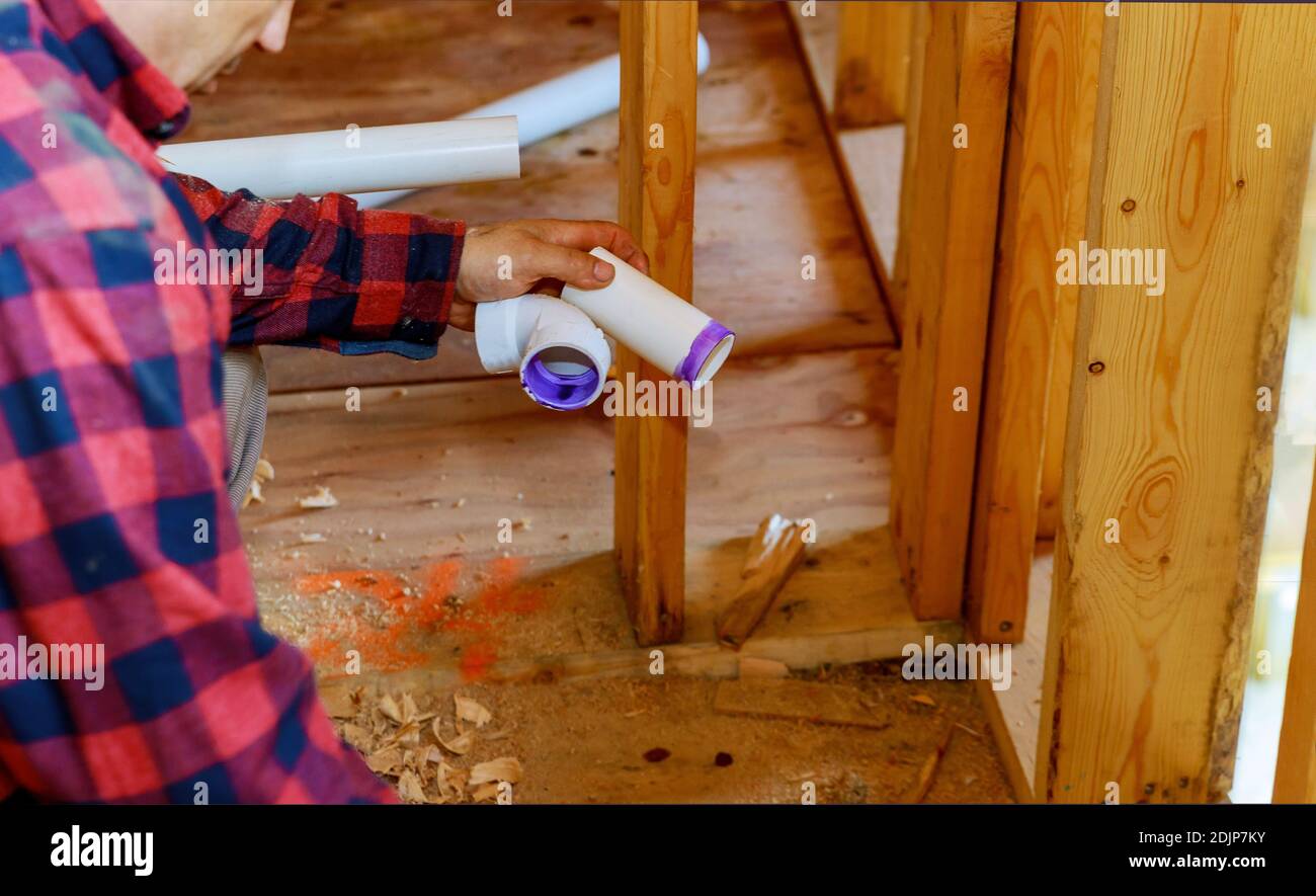 Plumber gluing sewage drain PVC pipes on home under construction Stock