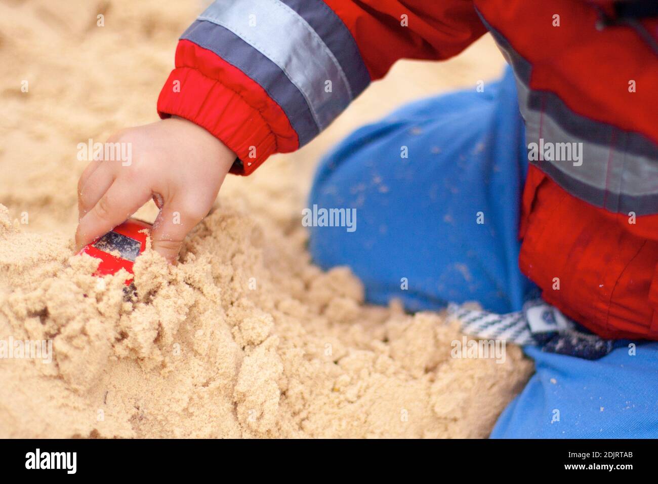 Midsection Of Boy Playing With Toy Car On Sand At Beach Stock Photo