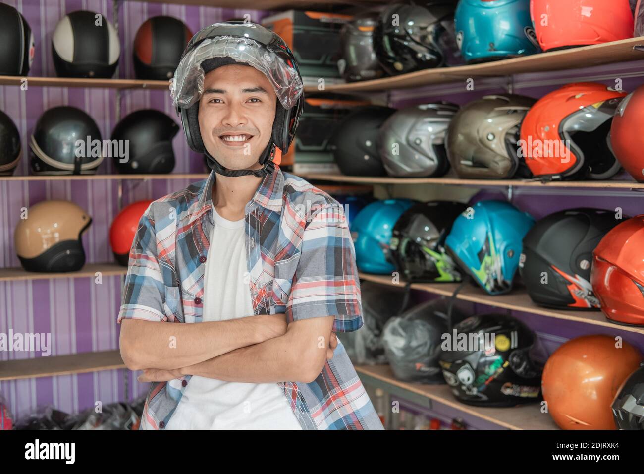 smiling man wearing helmet with crossed hands in helmet display rack