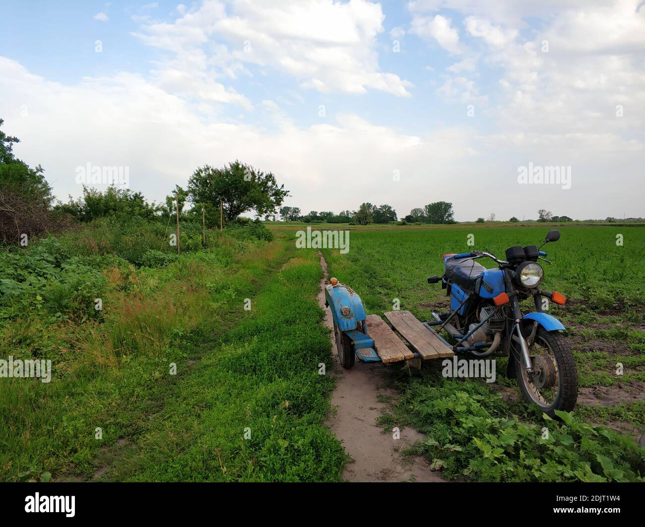 Old motorcycle with a sidecar on a deserted village road in the field ...