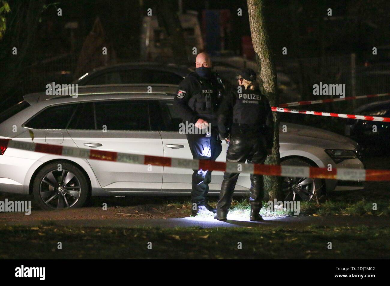 Hamburg, Germany. 14th Dec, 2020. Police officers search for evidence near  a crime scene with flashlights. A man was peeing on the side of the road in  Hamburg and was shot and