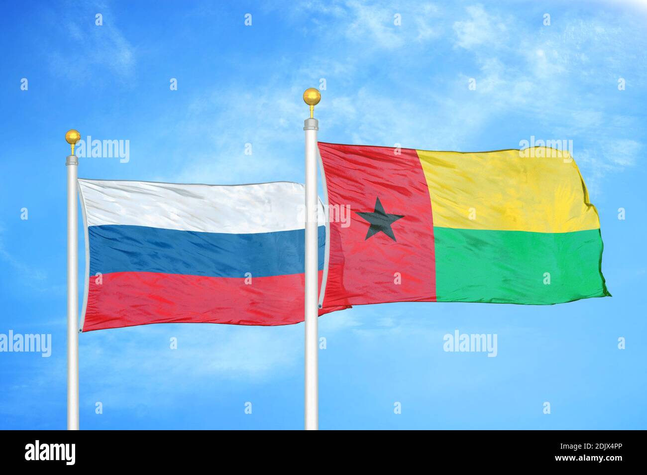 Russia and Guinea-Bissau two flags on flagpoles and blue cloudy sky Stock Photo