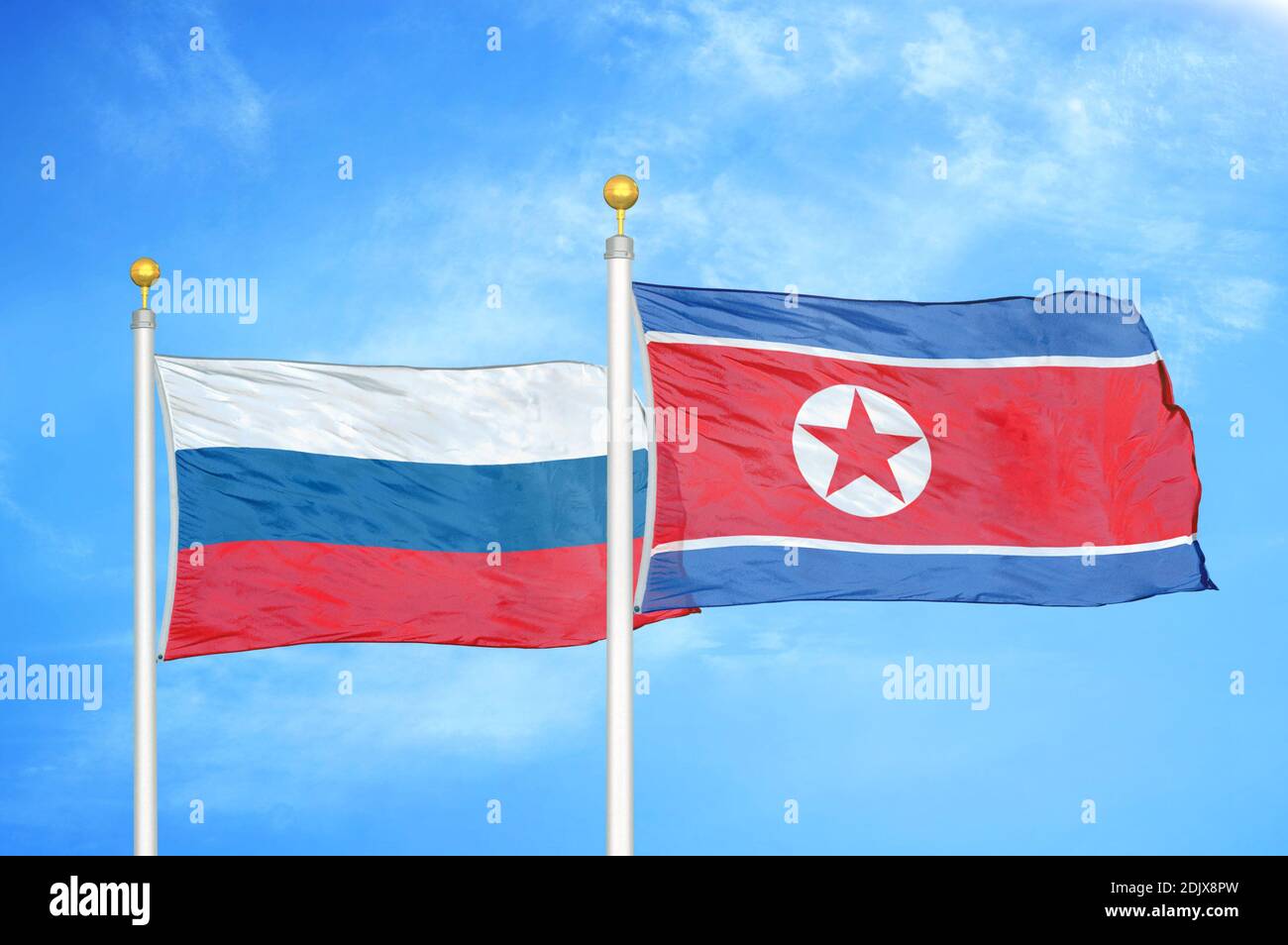 Russia and North Korea two flags on flagpoles and blue cloudy sky Stock Photo