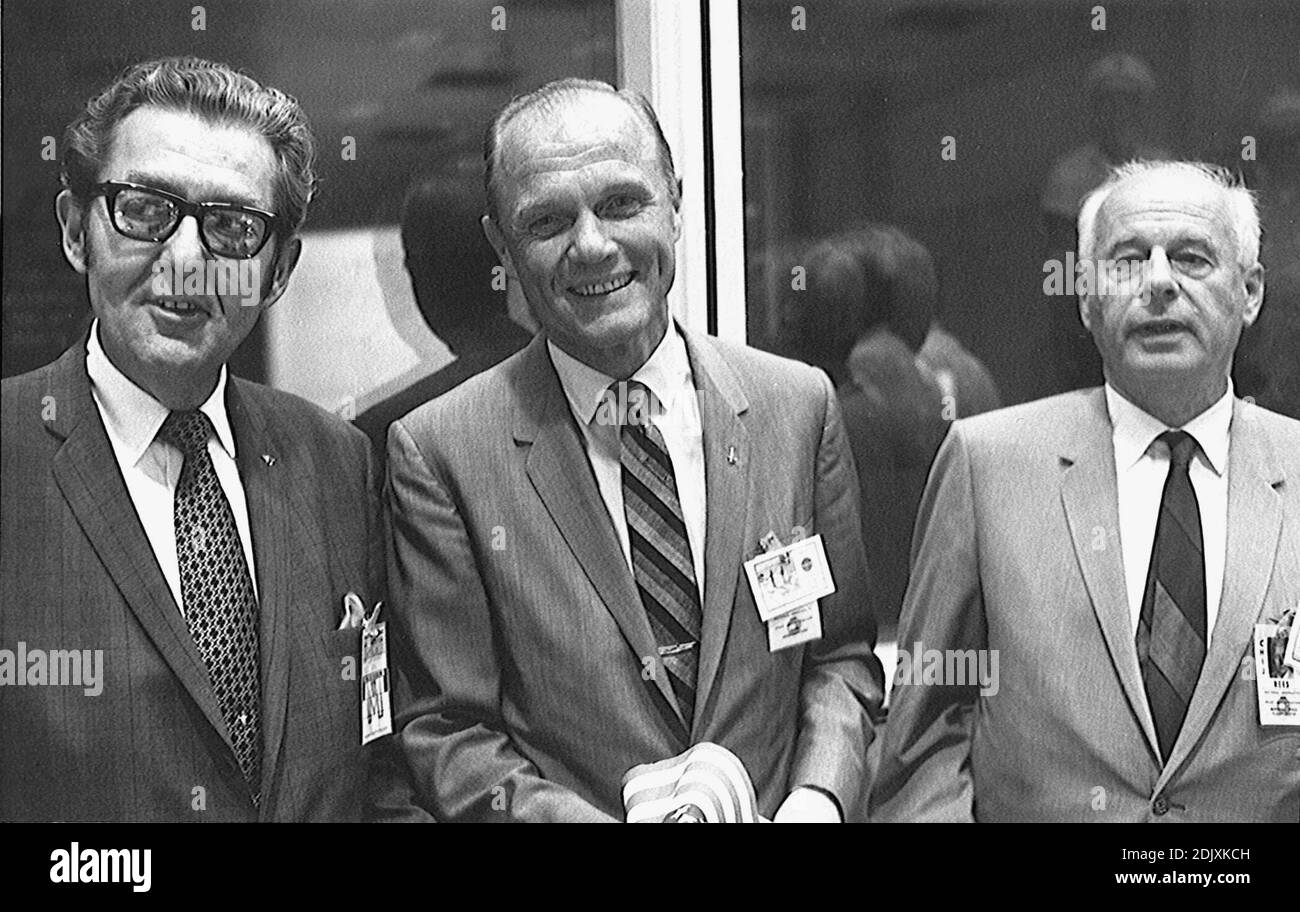 On hand in Houston's mission control center to witness activity associated with the landing and recovery operations for the Apollo 11 mission on July 24,1969 were, from the left, Bob Kline, chief of the Mission Operations Procurement Branch at the Manned Spacecraft Center (MSC); astronaut John H. Glenn Jr.; and Eberhard Rees, deputy director of the Marshall Space Flight Center (MSFC). They were among a large number of personnel on hand in the MCC's mission operations control room (MOCR). Glenn holds one of the dozens of flags that were handed out for the return's celebration. Photo by NASA via Stock Photo