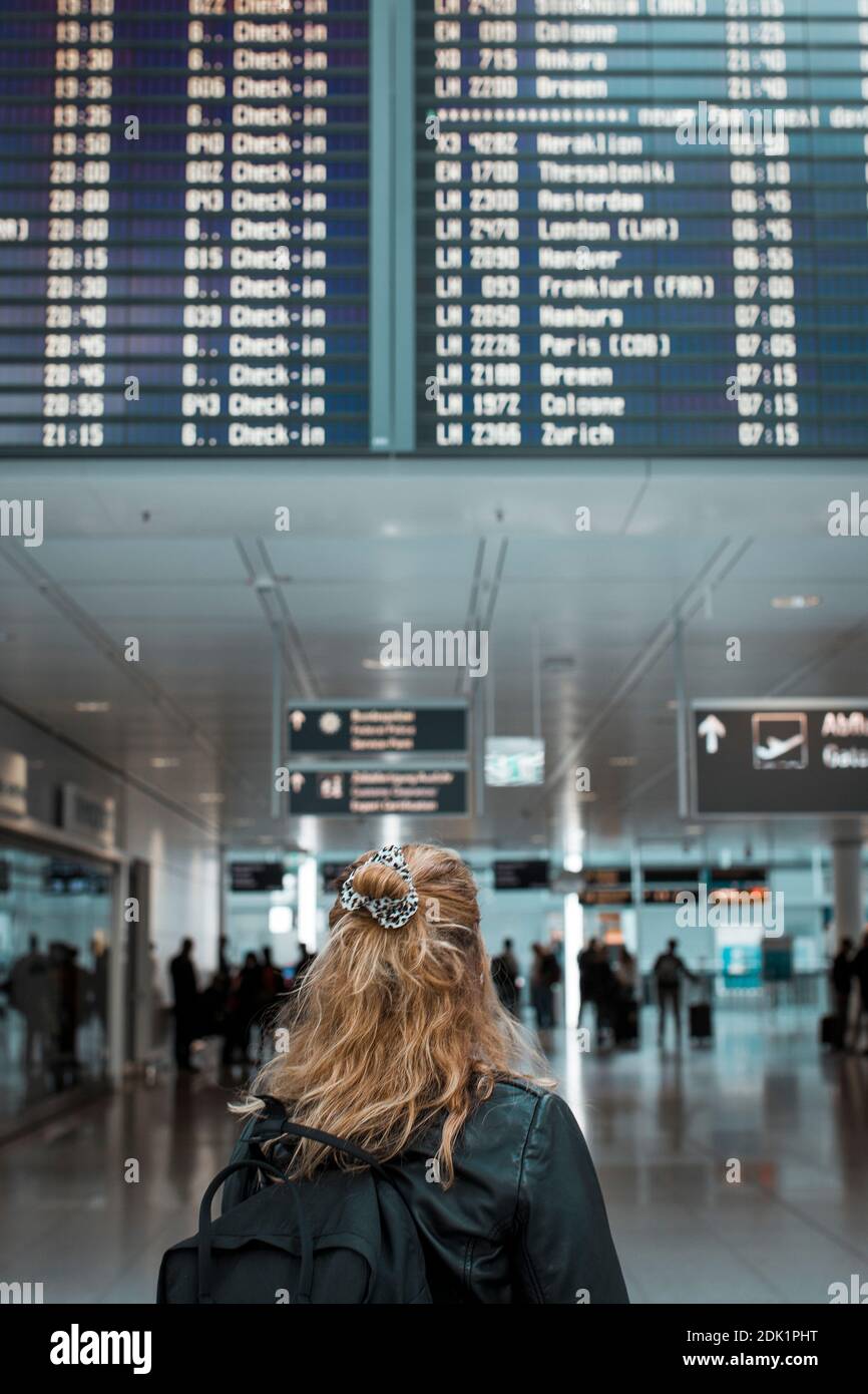 Junge blonde Frau am Flughafen München mit Mund-Nasen-Maske / Corona-Reise / Fluggast mit Schutzmaske Stock Photo