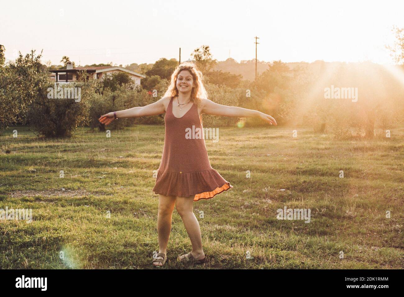 Young blonde woman with zest for life, dancing between olive trees in the sunset in Sardinia Stock Photo