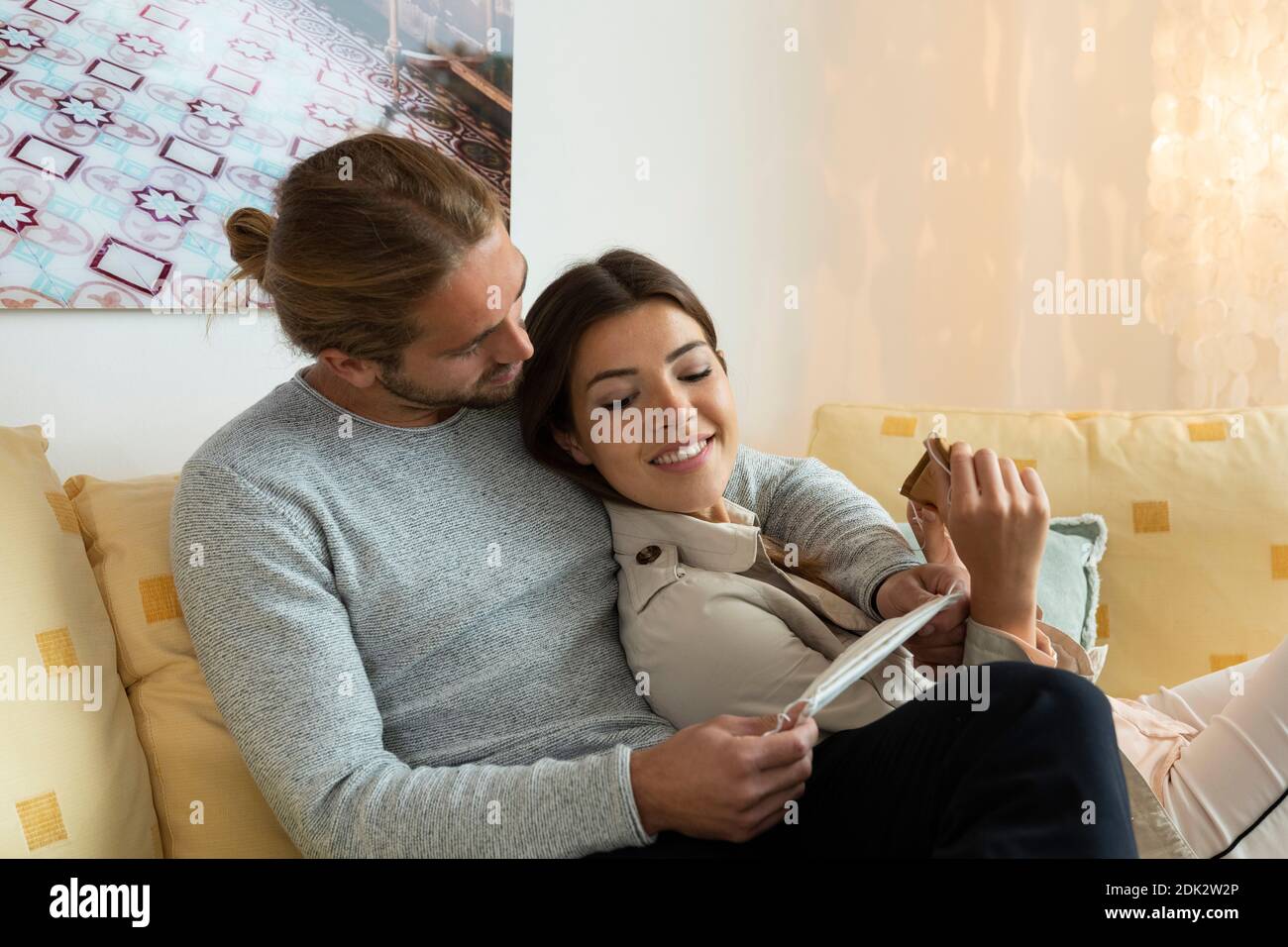 young couple with mouth and nose mask on the couch Stock Photo