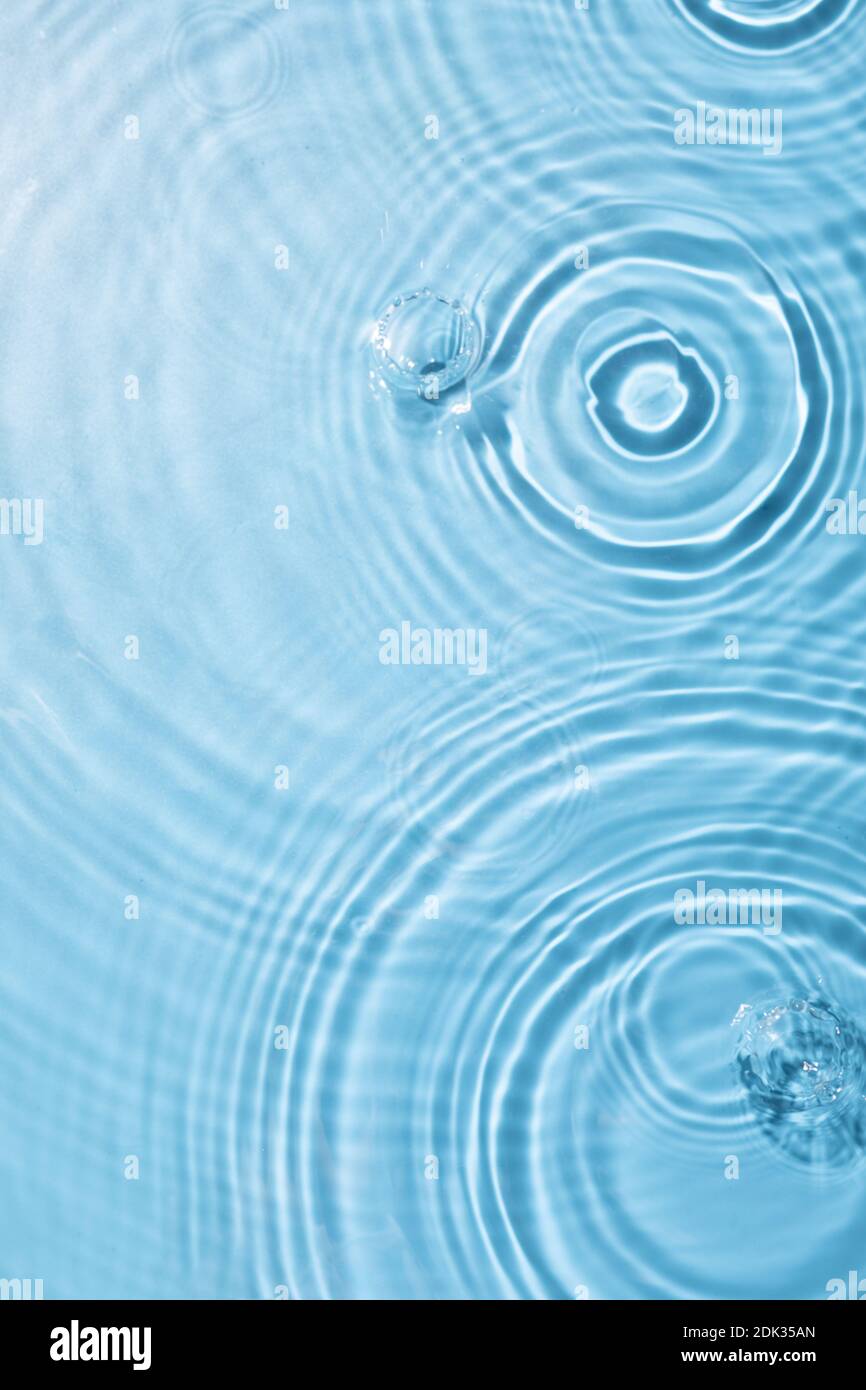 A top view closeup of waterdrops falling on the surface and forming a ...