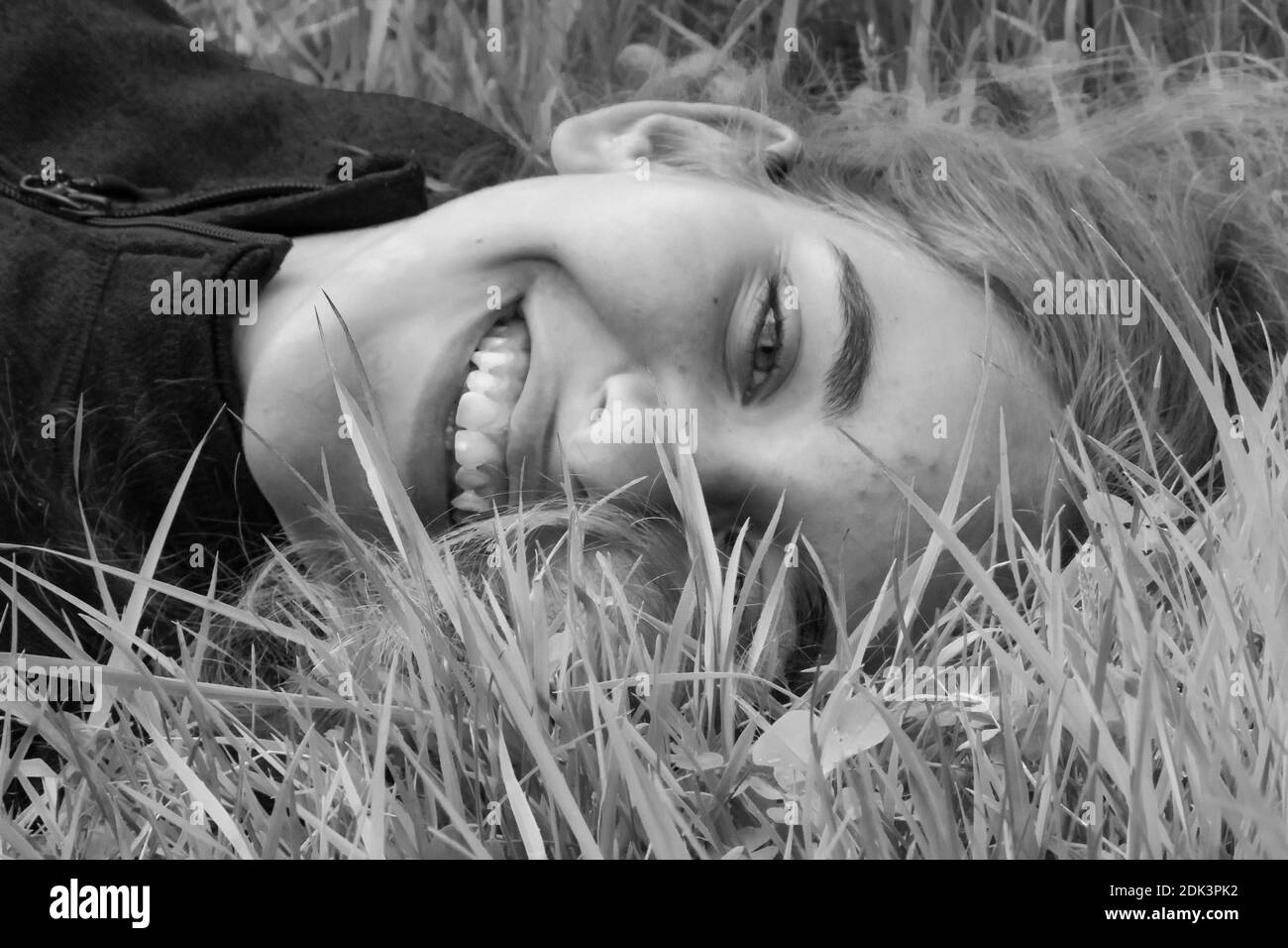 Close-up Portrait Of Smiling Woman Lying On Field Stock Photo