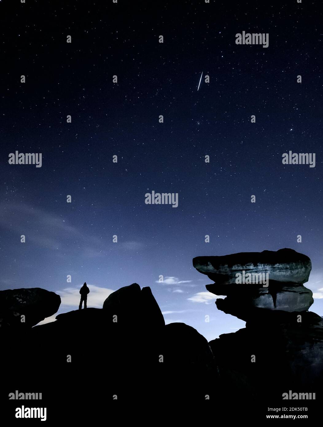 A man watches a meteor during the Geminid meteor shower over Brimham Rocks, a collection of balancing rock formations in the Nidderdale Area of Outstanding Natural Beauty in North Yorkshire. Stock Photo