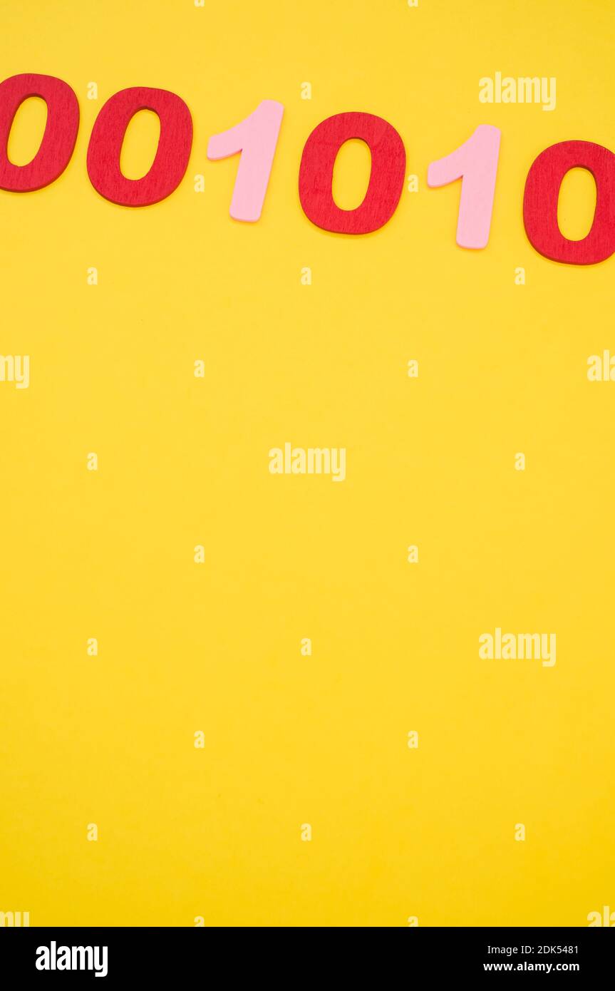 A vertical shotof red and pink binary codes on a bright yellow surface Stock Photo