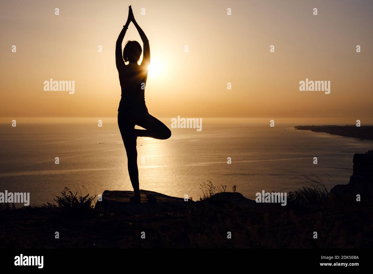 The woman with yoga posture on the mountain at sunset Silhouette of gorgeous young woman practicing yoga outdoor. wellness, healthcare, sport and life Stock Photo