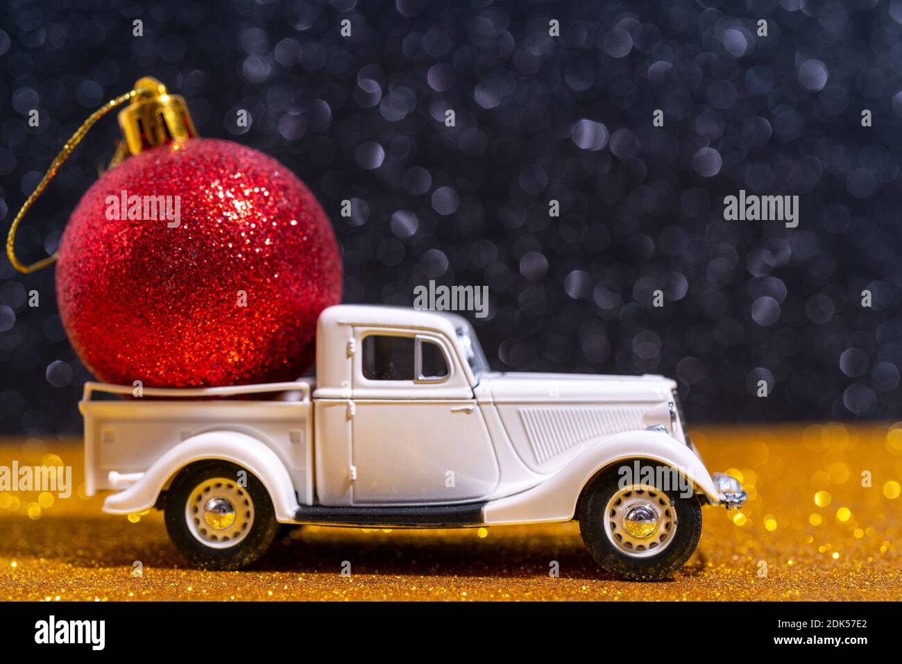 A small toy car delivering a shiny red Christmas ball Stock Photo