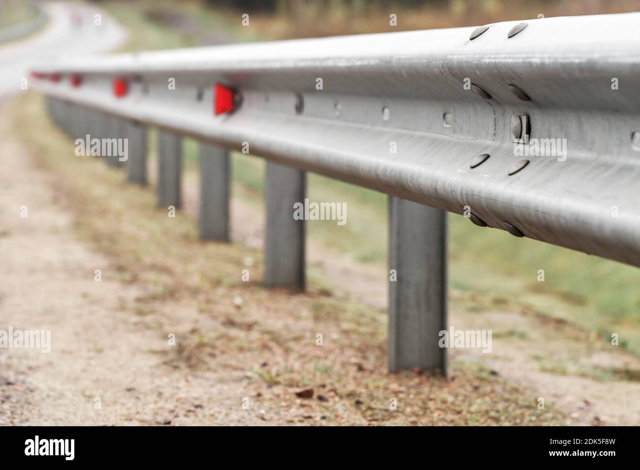 Metal guardrail with retro-reflecting optical units. Highway safety equipment, close-up photo with selective focus Stock Photo